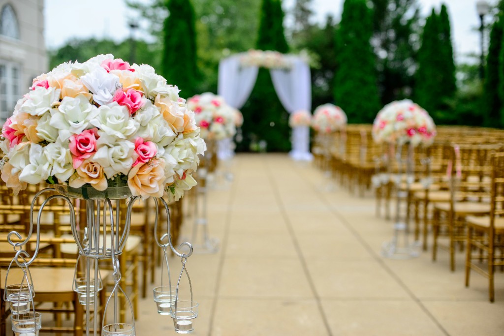 A wedding aisle lined with gold chairs and pink and white roses