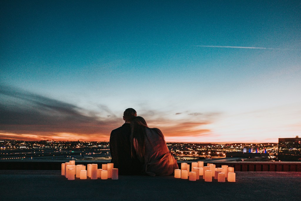 A couple watching a city sunset, surrounded by candles