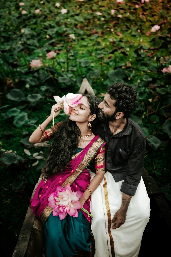 A couple beside a lotus pond, the bride in a magenta sari